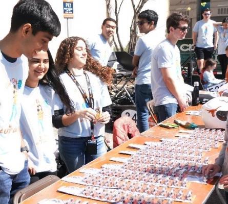 Group of people standing behind a table full of matchbox cars