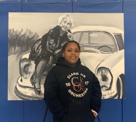 Girl standing in front of a black and white painting of a woman sitting on the hood of a car
