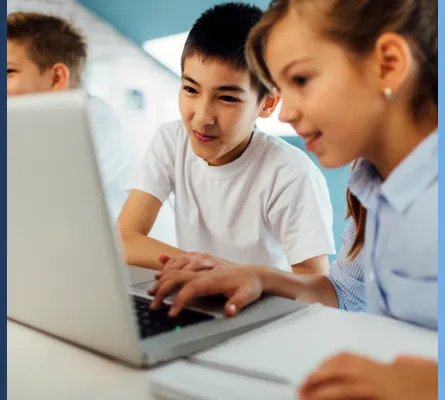 Two children look at a laptop