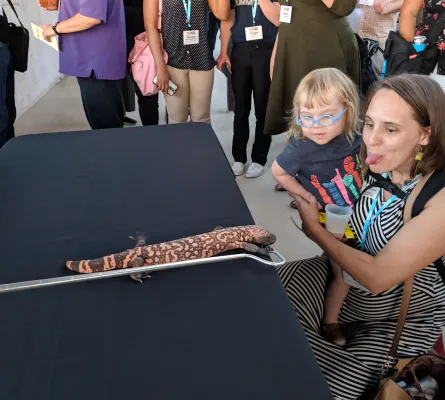 Sara with her daughter looking at a large lizard