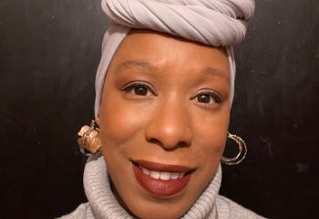 Woman wearing light brown head wrap and shirt