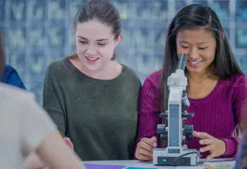 two girls looking through a microscope 