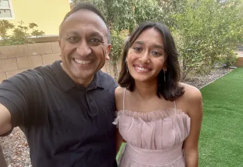 Father and Daughter in yard with stone wall, grass, and trees