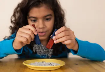 Young girl playing with red and blue bar magnets and metal filings