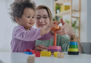 a child supported by a woman playing with STEM toys
