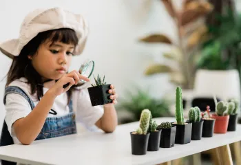 young girl looking at plants with a magnifying glass