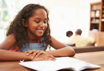 Young girl reading a book on a table