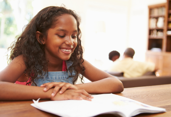 Young girl reading a book on a table