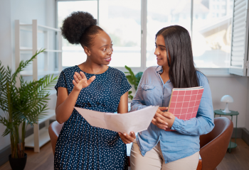 Photo of woman holding papers talking to a teen girl