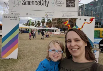 Woman with young daughter in front of a banner reading ScienceCity