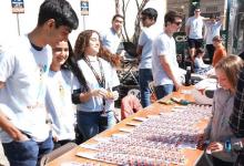 Group of people standing behind a table full of matchbox cars