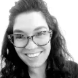 Claire Quimby - black and white photo of a woman with curly, dark hair, wearing glasses