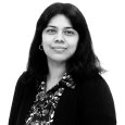 Lalitha Krishnamoorthy - black and white photo of a owman with dark hair wearing a floral print top and dark sweater