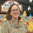 Marie Brennan - Woman with brown hair and glasses standing in front of a library display