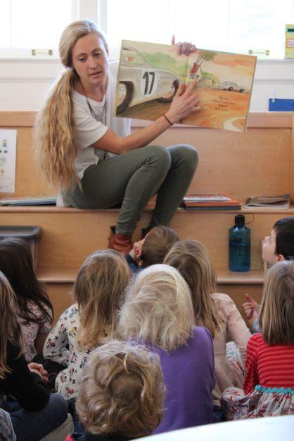 Blonde woman shows a picture book to a group of young children