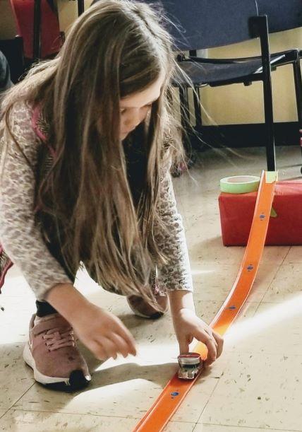 Girl holding matchbox car on orange track