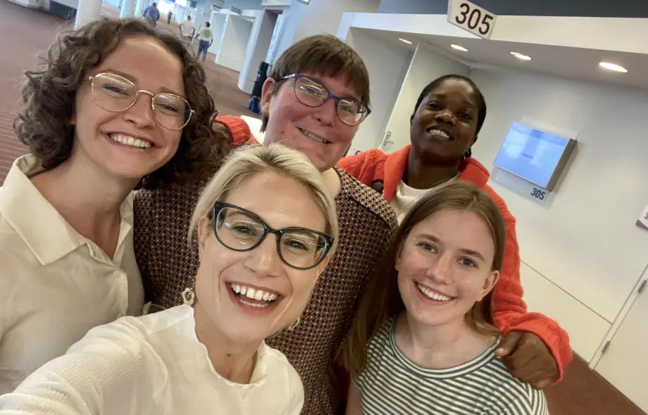 A selfie of five people looking at the camera and smiling. 