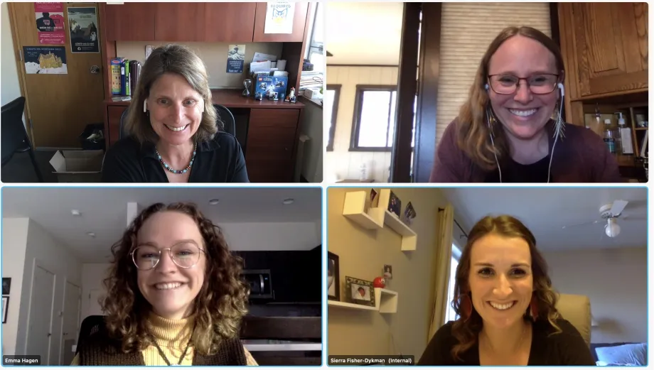 A screenshot of 4 people on a virtual call together. All four are smiling and looking at their screens. 