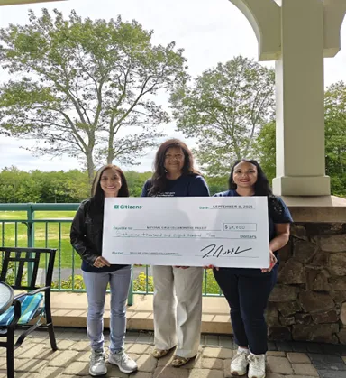 Three women holding a large check